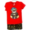 A 2-piece set for boys consisting of a red t-shirt with a graphic of a bear in a cap and sunglasses, paired with black shorts featuring a gold geometric pattern.