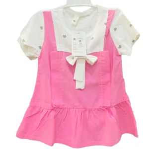 A cute girls' dress featuring a white top with a grey heart print layered under a bright pink pinafore with a white bow detail.